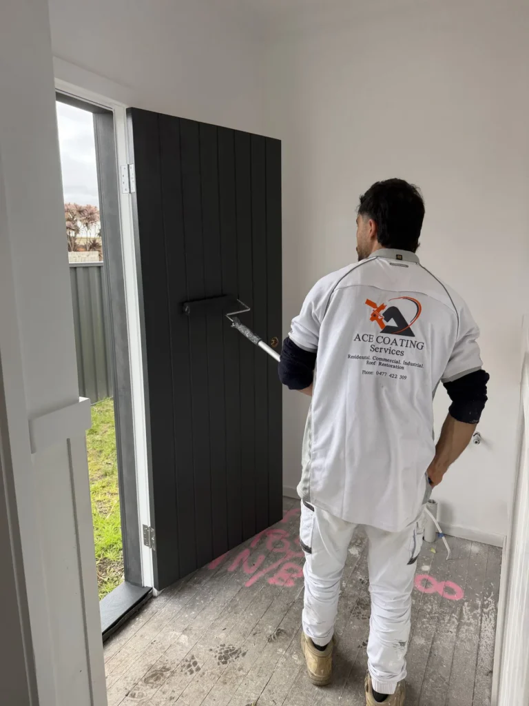 Ace Coating Services painter applying black paint to a timber door with a roller