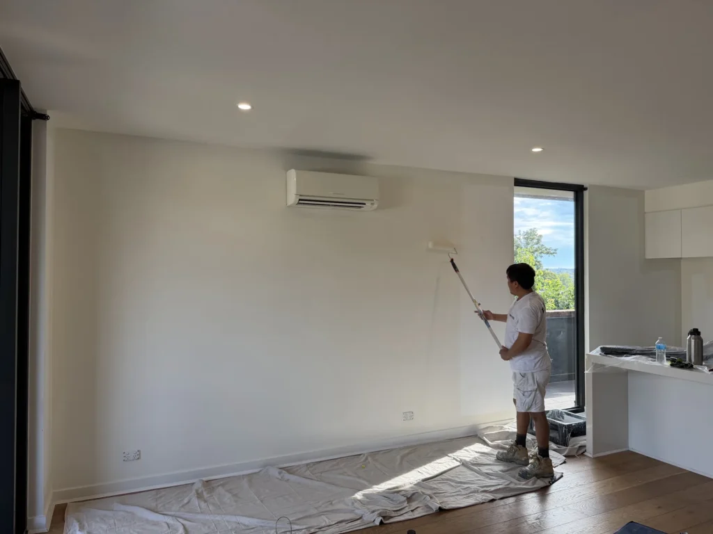 Ace Coating Services painter rolling fresh paint onto a living room wall – interior painting Melbourne