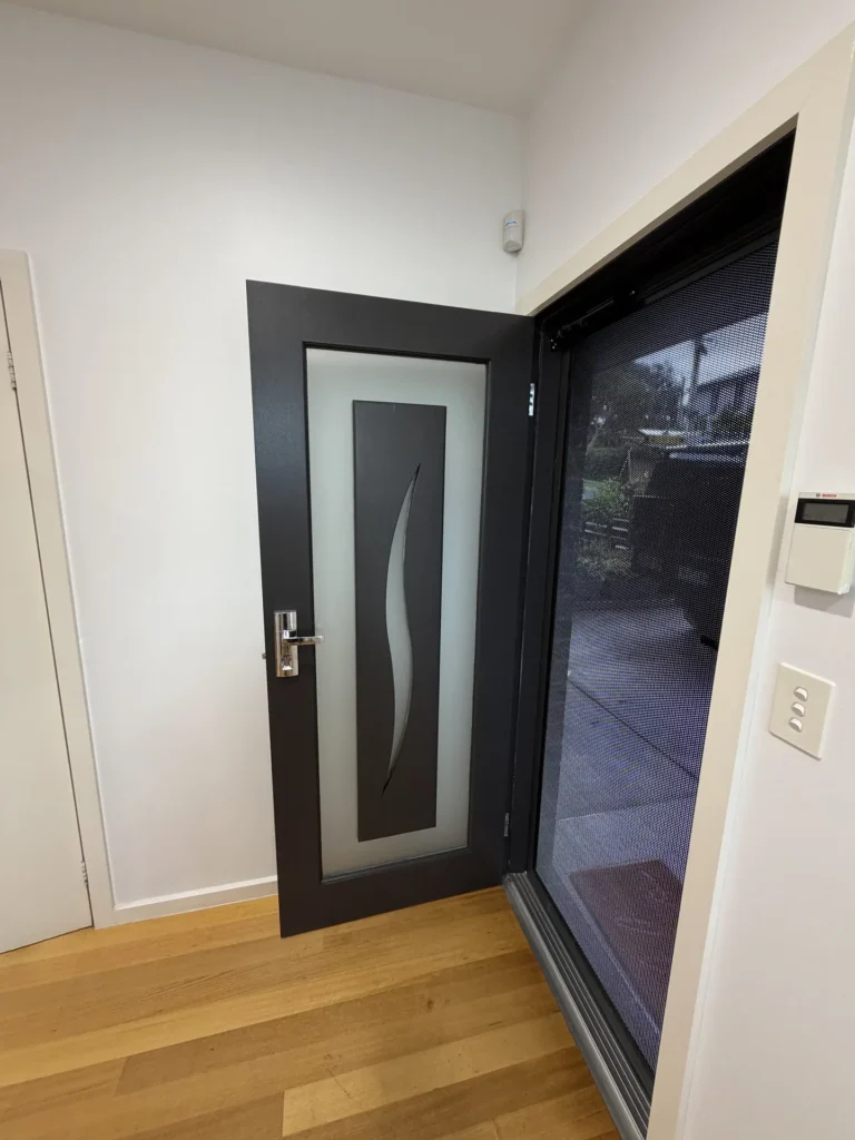 Painted black entry door with fresh white walls and timber flooring – residential painting by Ace Coating Services