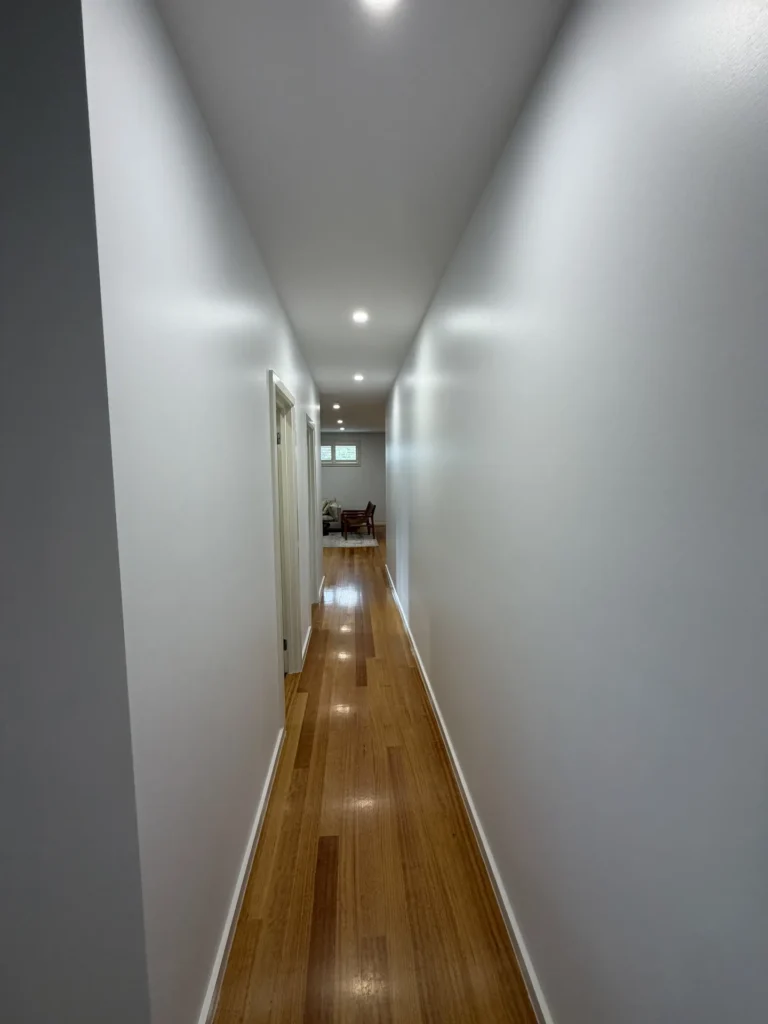 Long hallway with freshly painted white walls and timber floors – interior painting Melbourne by Ace Coating Services