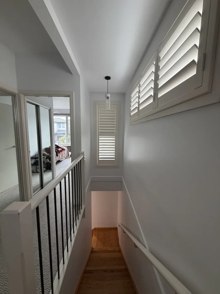 Freshly painted white stairwell with plantation shutters – interior painting Melbourne by Ace Coating Services