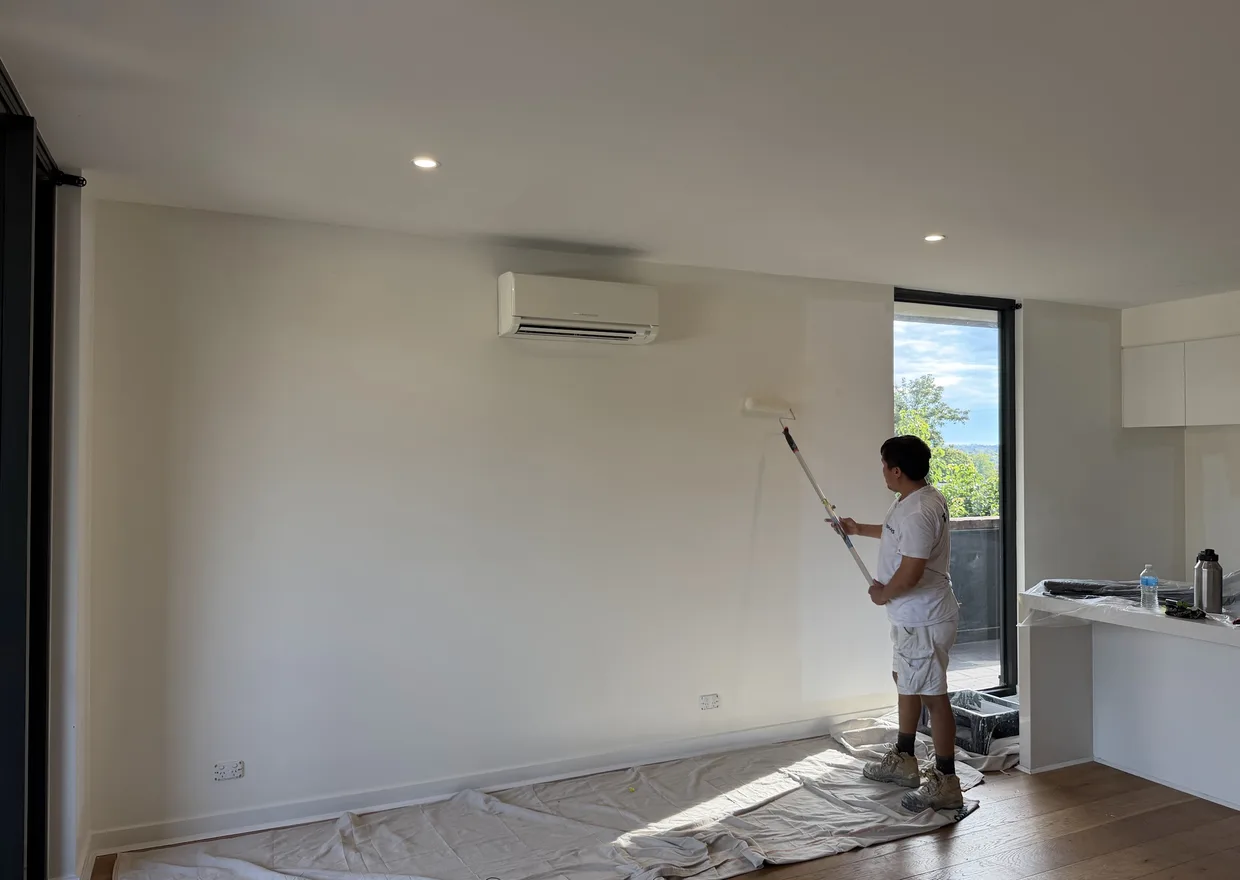 Ace Coating Services painter rolling fresh paint onto a living room wall in Melbourne